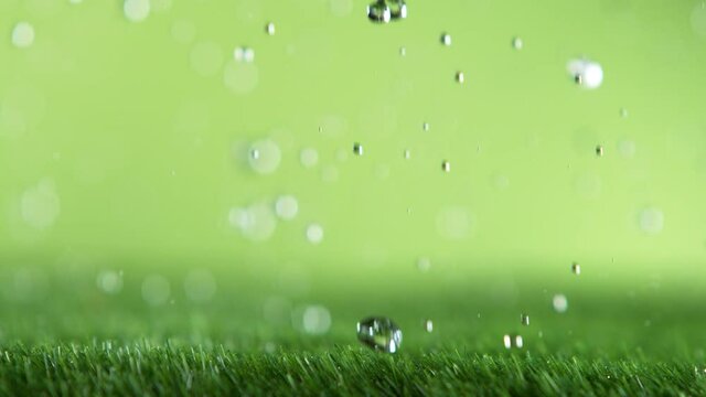 Super slow motion of falling water drops on green lawn, macro shot. Filmed on high speed cinema camera, 1000fps.