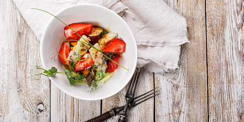 Food banner. Delicious summer salad. Salad with fresh strawberries, baked beets, yellow tomatoes, dor blue cheese and herbs in a white bowl on a light rustic background. Summerfood. Copy space