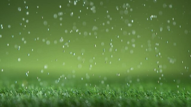 Super slow motion of falling water drops on green lawn, macro shot. Filmed on high speed cinema camera, 1000fps.