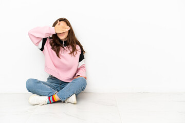 Young caucasian woman sitting on the floor isolated on white background covering eyes by hands. Do not want to see something