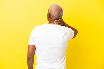 Cuban Senior isolated on yellow background in back position and thinking