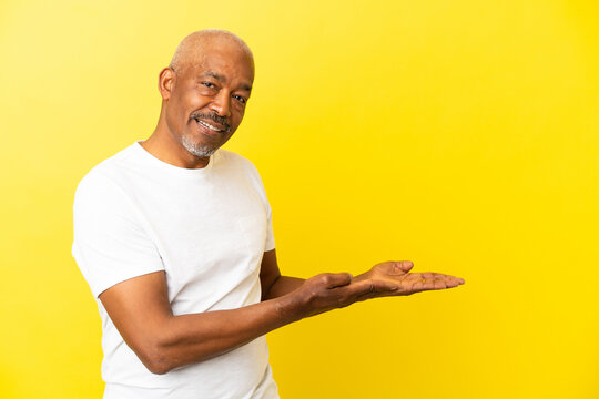 Cuban Senior isolated on yellow background extending hands to the side for inviting to come
