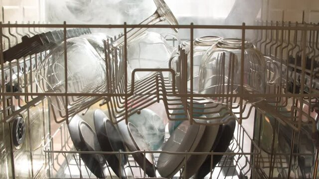 View from the Dishwasher. View from the dishwasher to the outside. The door opens and clouds of steam burst out, illuminated by a bright light