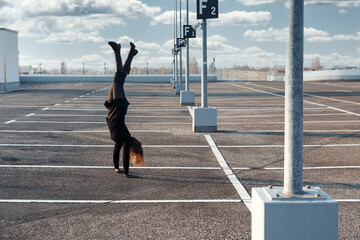 brunette woman making a handstand in empty parking lot outdoors