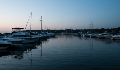 Fototapeta premium A harbor/marina filled with sailboats during a blue/orange sunset in Port Elgin, Ontario, Canada.