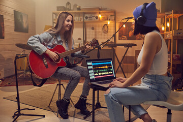 Two young women recording new music in front of laptop