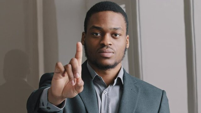Headshot close up view 25s mixed race young guy standing indoor look at camera stretch out hand, waving index finger, say stop racism and racial discrimination, corruption. Social problems concept