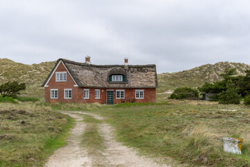 Fototapeta na wymiar traditional Danish house with thatched reed roof in a coastal sand dune landscape