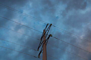 Concrete tower of power lines against the background of a blue sky with clouds