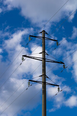 Concrete tower of power lines against the background of a blue sky with clouds