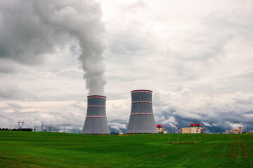 Steaming Cooling towers of nuclear power plant against the cloudy dramatic sky in Ostrovets, Grodno...