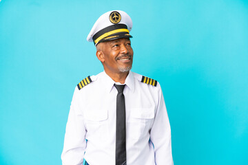 Airplane pilot senior man isolated on blue background thinking an idea while looking up