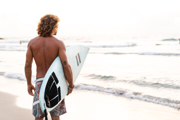 Young caucasian man get up early to  doing surf at sunrise - obrazy, fototapety, plakaty