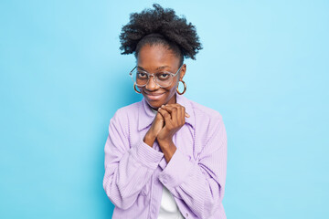 Photo of nice looking dark skinned woman keeps hands together feels glad and shy accepts compliment...