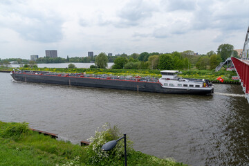 large riverboat barge tranporting goods along the wide canals of Amsterdam