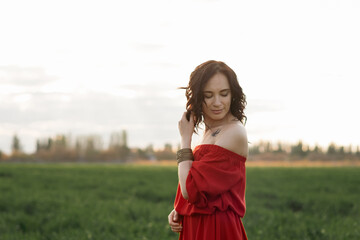 beautiful hispanic young woman in red dress dancing in a field at sunset