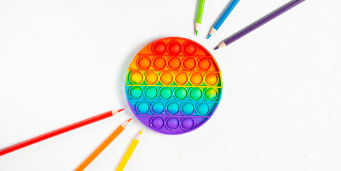 Rainbow silicone antistress pop it or simplele simple with multicolored pencils on white background