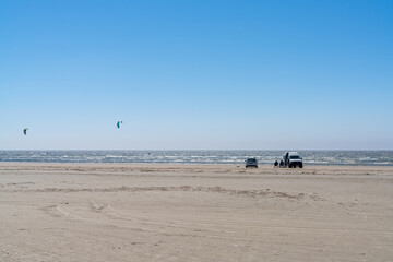 Fototapeta na wymiar van life kite surfers parked on a golden beach next to the ocean
