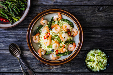 Risotto with prawns and asparagus on wooden background
