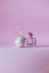 White bath bomb next to a small vase on a pink background.