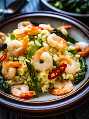 Risotto with prawns and asparagus on wooden background
