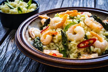 Risotto with prawns and asparagus on wooden background
