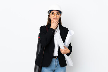 Young architect caucasian woman with helmet and holding blueprints over isolated background thinking an idea
