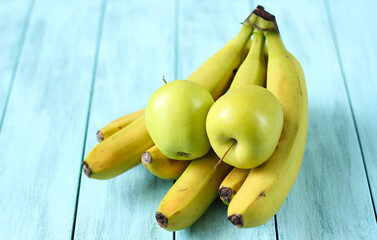Yellow bananas and green apples on a blue wooden background, healthy food concept. 