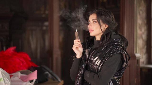 Woman Smoking tobacco heater system dressed black jacket close up portrait
