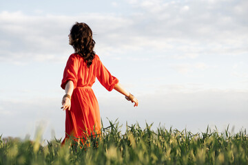 beautiful hispanic young woman in red dress whirls in a field at sunset