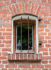 Old window with iron bars in a brick stone wall