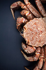 Cast-iron pan with boiled horsehair crab, flatlay over dark brown stone background, studio shot