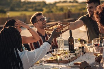 Group of friends at reunion eating and drinking wine.