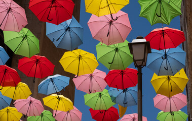 Street decorated with colored umbrellas. Multicolored parasols above narrow pedestrian street of the old city.