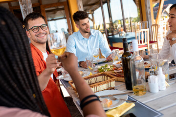 Group of friends at reunion eating and drinking wine.