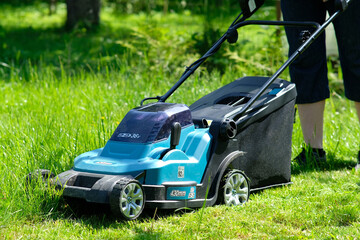 Fototapeta na wymiar Electric lawn mower on the green grass, garden equipment.