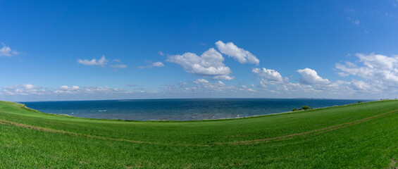 sloping green grass farm field leading down to the shores of the North Sea at the Limfjord in northern Denmark