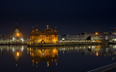 Fototapeta na wymiar Amritsar, India : Wide angle shot of Harmindar Sahib, aka Golden Temple Amritsar. Religious place of Sikhism. Sikh gurdwara in the holy pond at night with reflection