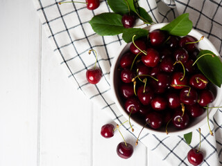 fresh cherries in a white bowl on a white wooden table