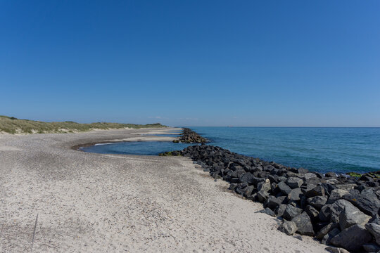 beautiful empty beach behind sand dunes with rocky storm groins to protect from erosion