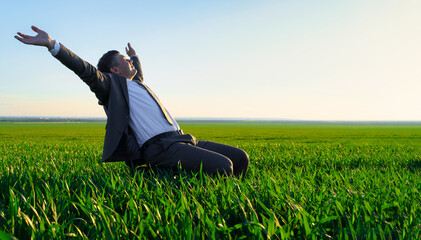 businessman sits in an office chair in a field and rests, freelance and business concept, green grass and blue sky as background