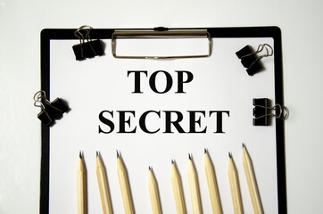 Top Secret the word is written on a white piece of paper with pencils