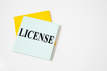 license word written on gray background with pencils and paper clips