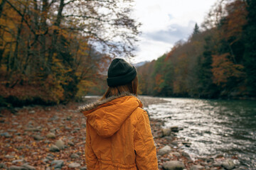 woman walking along the river fallen leaves autumn travel