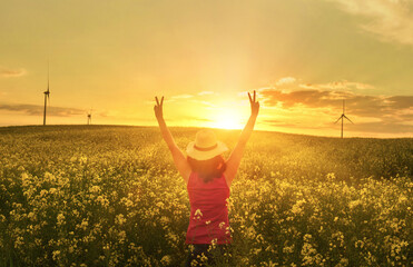 Happy woman giving the victory sign in the sunshine on sunset flower field