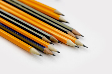 few sharply sharpened pencils of different color on the white table. selective focus
