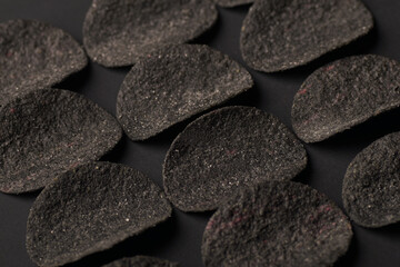 Black chips and red hot peppers on black background