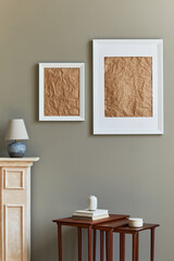 Stylish and luxury interior with white mock up poster frame, vases, books, wooden stools, mug and elegant accessories in home decor. Template.