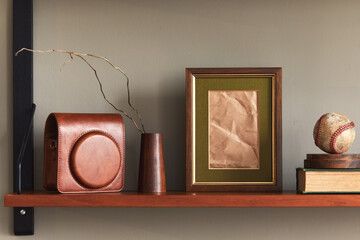 Minimalist composition on wooden shelf with brown mock up picture frame, clock, vase, camera case...