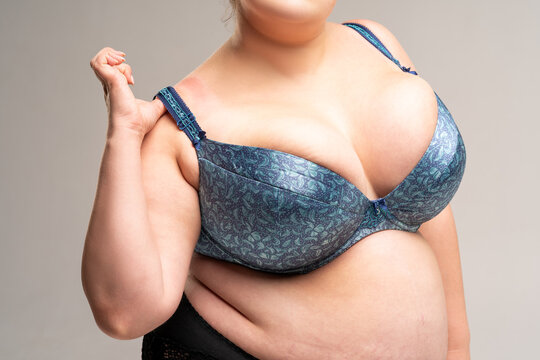 Large natural breasts in blue bra, biggest boobs on gray background